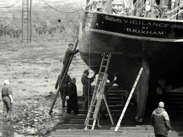 Black and white image of men working on a vessel taken by Peter Hunt 