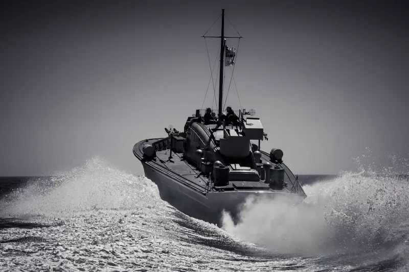 Black and white image of MGB81 from the stern going at considerable speed, the water behind her foaming and splashing