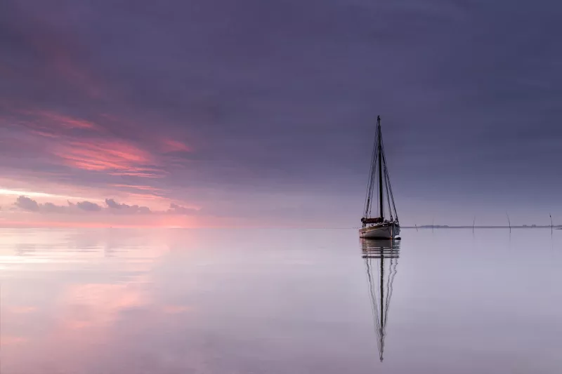 Smack moored on a calm day, with the pink and purple sky reflected in the water below