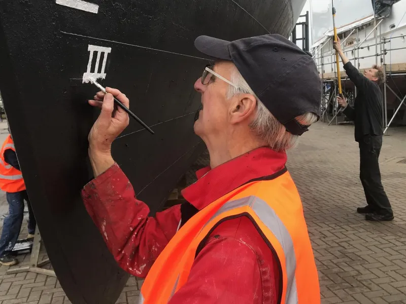 Brian Small painting the Plimsoll line on HMS Medusa