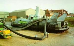 BH7 is saved from scrap. A giant Air Blower ducts air under the engineless craft and lorries of the Royal Navy tow her ashore into storage December 1989.